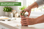A person's hands using a green finger wrap to open a glass jar on a kitchen counter, with a green text banner in the top left reading 'GRIP, TWIST, MOVE AND HOLD WITHOUT STRUGGLING'.